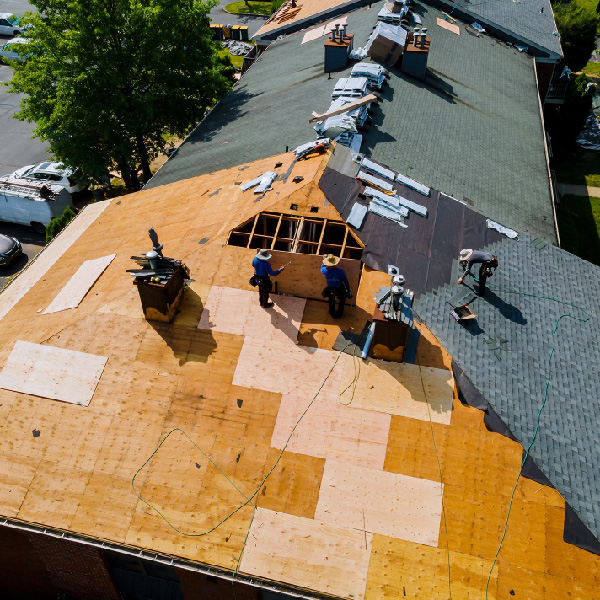 Commercial roofing contractors in Tampa performing roof replacement on a large building with exposed decking and active repair work