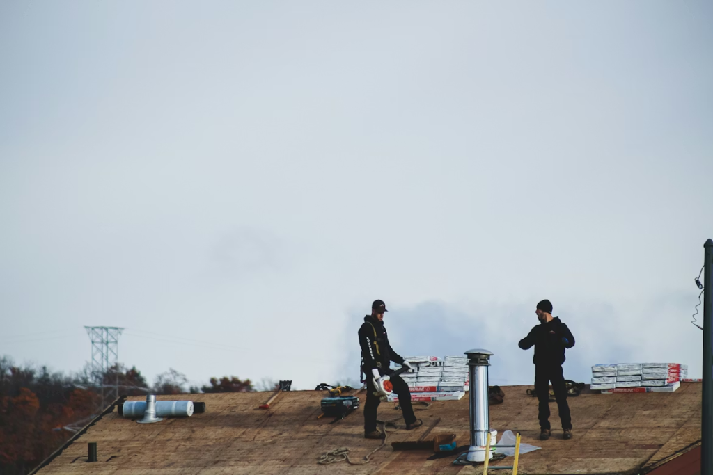 men standing on top of a flat roof with a chimney
