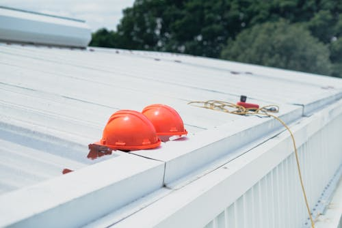 Two orange construction hats on a white roof