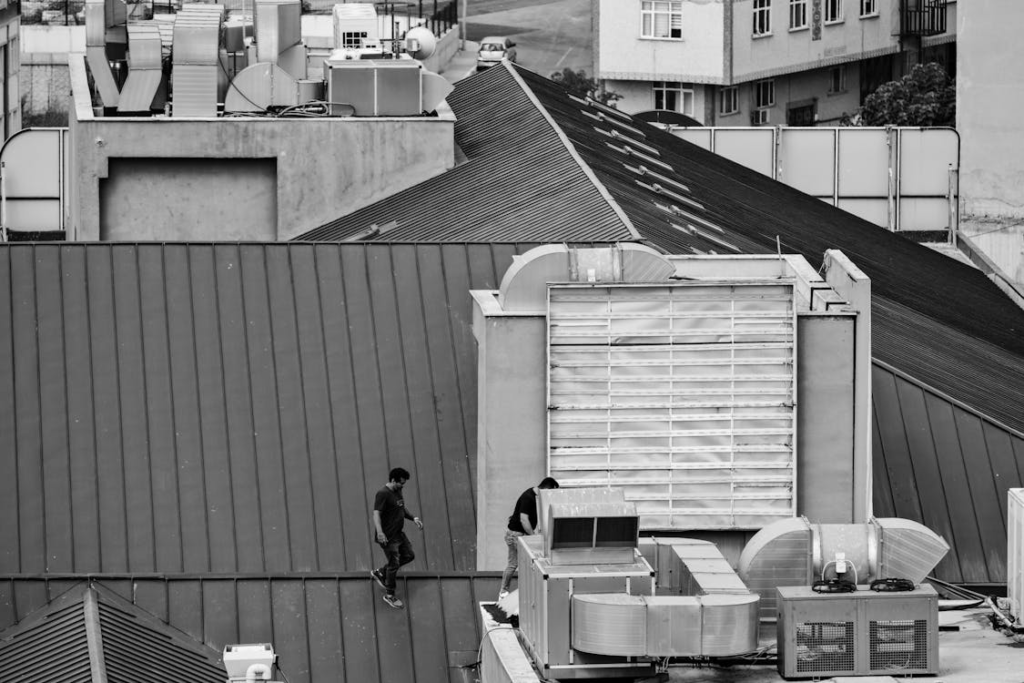 a man walking towards the HVAC system on top of a roof