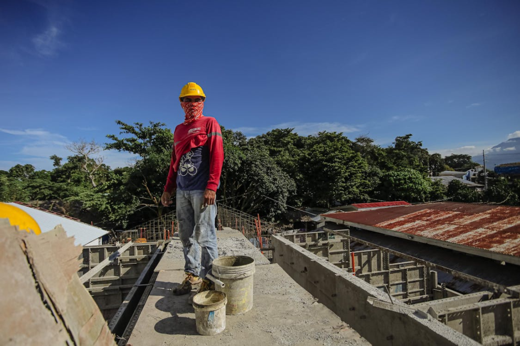 a worker working on top of the roof wearing a cloth around his face