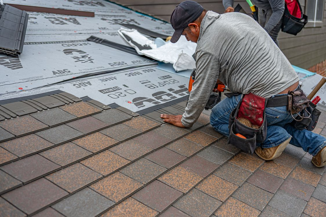 A roofer installing shingles