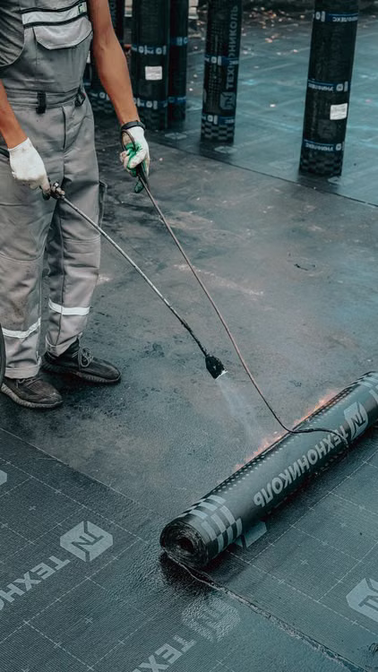 Roofing professional applying a protective coating to a low-slope commercial roof