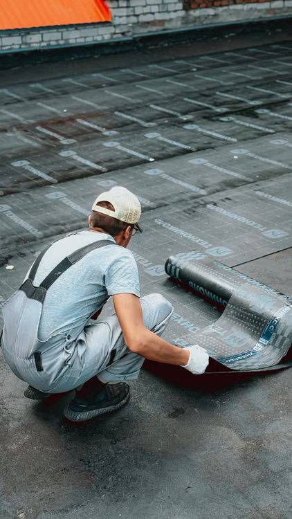 Worker rolling roof membrane